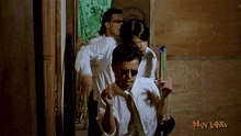 a man in a white shirt and tie is holding a green object in front of a man laksa logo