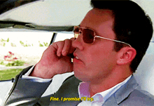 a man wearing sunglasses and a suit is talking on a cell phone and says fine i promise i 'll try