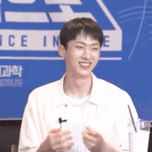 a young man is holding a microphone and smiling in front of a sign that says ice in e.