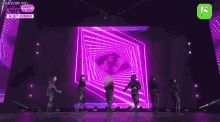 a group of people are dancing on a stage in front of a large screen .