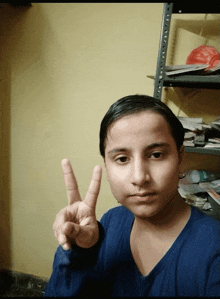a young boy in a blue shirt is giving the peace sign