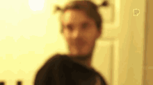 a blurry picture of a man with pigtails on his head standing in front of a door .