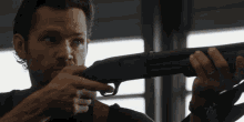 a man is holding a shotgun and pointing it at something