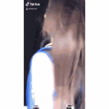 a woman with long hair is wearing a blue and white shirt and a tiktok account