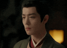 a close up of a man 's face with a green jacket and a red tie .