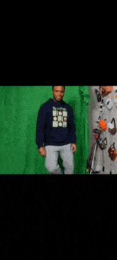 a man wearing a rick and morty sweatshirt is dancing in front of a green screen