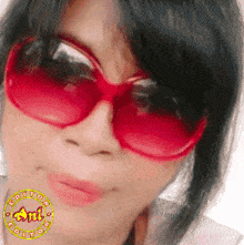 a close up of a woman wearing red sunglasses with an ant editor sticker