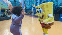 a woman stands next to a spongebob mascot in an amusement park