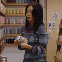 a woman in a striped sweater holds a ball of yarn with a label on it that says ' wool '