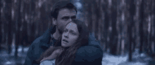 a man is holding a woman in a forest .