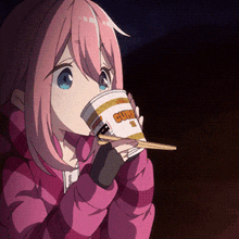 a girl is drinking from a cup of curry with chopsticks