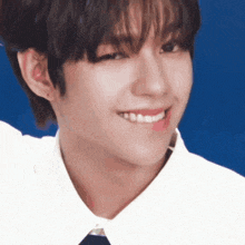 a close up of a person 's face with a blue background and a white shirt and tie .