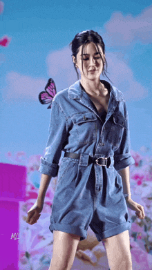 a woman in a denim jumpsuit is dancing with a butterfly behind her