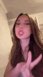 a woman with long hair is making a peace sign with her hands .