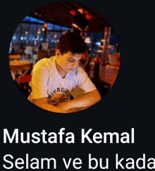 mustafa kemal is sitting at a table with his hands on a table