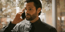 a man with a beard talks on a cell phone