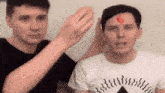 two men are standing next to each other and one of them has a red number 6 on his forehead .