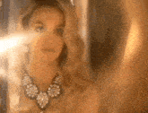 a woman is taking a selfie in front of a mirror while wearing a necklace and earrings .