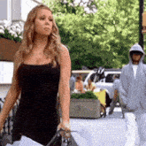 a woman in a black dress walking down a street