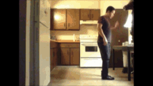 a man in a black shirt is standing in a kitchen near a refrigerator
