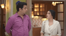 a man and a woman are standing next to each other in a room and talking to each other .