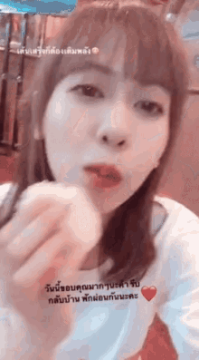 a girl with a heart on her shirt is eating a food item