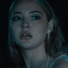 a close up of a woman 's face with a necklace and earrings