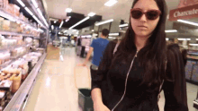 a woman wearing sunglasses walks through a grocery store aisle