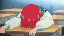 a girl with red hair is laying her head on her desk
