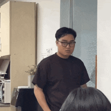 a man wearing glasses and a black shirt is standing in front of a woman