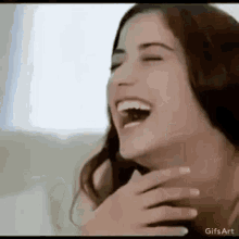a woman is laughing with her mouth open and covering her face .