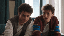 two young men are sitting next to each other on a blue couch