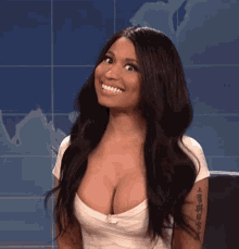 a woman with a tattoo on her arm is smiling with her breasts exposed .