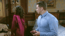 a man in a blue shirt is standing next to a woman in a pink robe