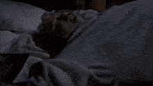 a man is laying on a bed with a woman standing behind him