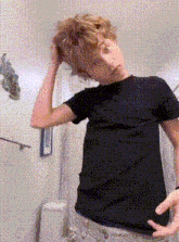 a young boy in a black t-shirt is standing in a bathroom