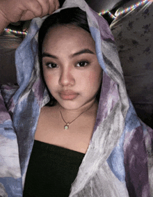 a woman is wrapped in a blanket and has a necklace on her neck