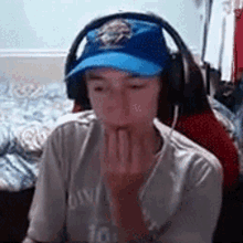 a young boy wearing headphones and a blue hat is sitting in a chair .