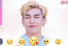a young man is making a funny face with a bunch of smiley faces around him .