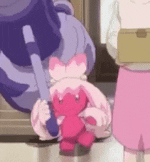 a pink stuffed animal with a bow on it is being held by a person .
