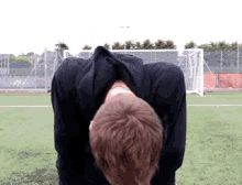 a man in a black shirt is standing on a soccer field