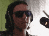 a man wearing headphones and sunglasses looks at the camera .