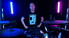 a man in a black shirt with the letter d on it playing drums