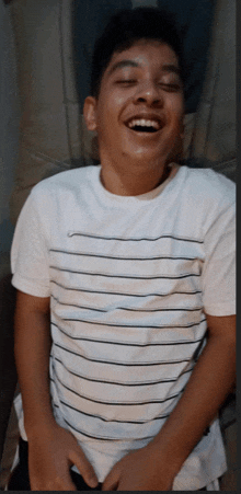 a young boy wearing a white nike shirt is laughing with his eyes closed