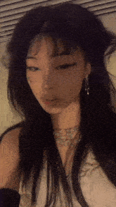 a girl with long black hair is taking a selfie with a butterfly tattoo on her face .