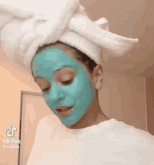 a woman wearing a blue face mask with a towel wrapped around her head .