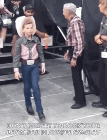 a young boy dressed as a cowboy is walking towards a man .