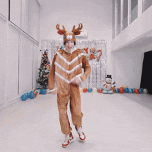 a person in a reindeer costume is dancing in front of a christmas tree