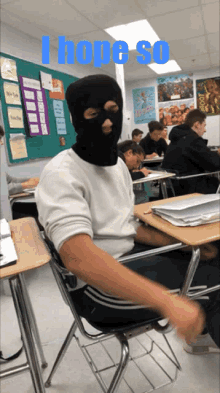 a man wearing a ski mask sits in a classroom with the words i hope so behind him