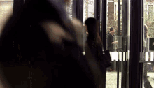a woman is walking through a doorway with a green exit sign
